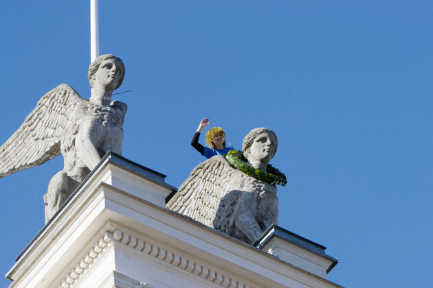 Person hanging a wreath around the neck of one of the university main building sphinx statues.