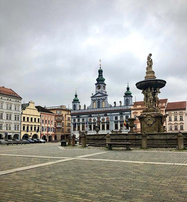 Ett stenlagt torg hyser en stor fontän med utsmyckningar och runt torget syns vackra byggnader i olika färger från 1700- och 1800-talen. Torget ligger i staden Český Krumlov i södra Tjeckien.