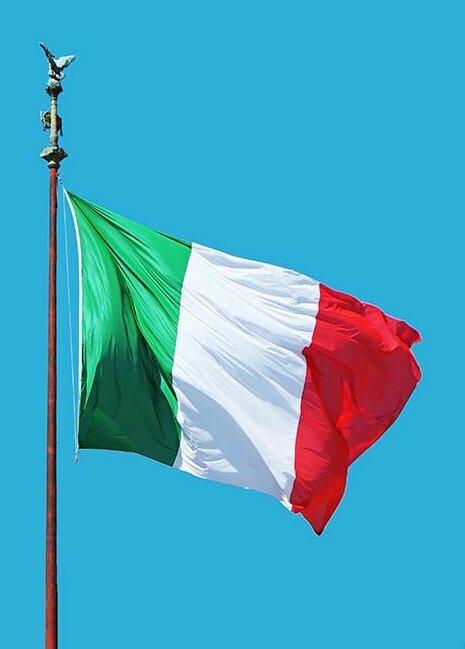 The Italian flag flies against a blue sky.