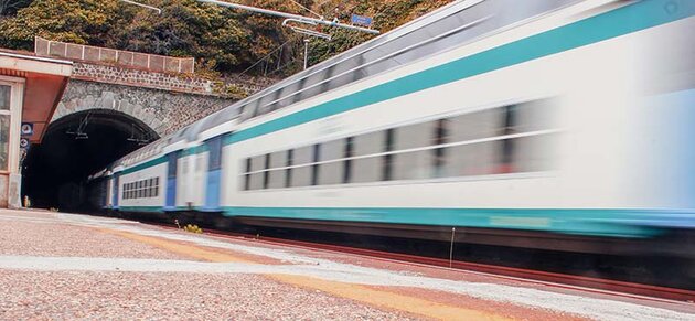 A train is travelling at full speed into a tunnel. It is so fast that most of the train is blurred.
