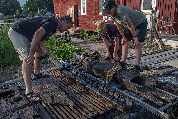 Arkeologerna Brendan Foley på Lunds universitet samt Mikkel Haugstrup Thomsen och Marie Jonsson från Vikingaskeppsmuseet i Roskilde undersöker en kanonlavett och andra skeppsdelar som bärgades från Gribshundsvraket 2021. Foto: Brett Seymour