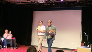 Vinnaren Matthew Tompkins går över scenen när han har vunnit med blommor i handen.
