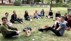 På gräsmattan utanför SOL nedanför UB1 sitter ett gäng av utbytesstudenterna i en stor ring med sina bruna lunchpåsar. Foto.