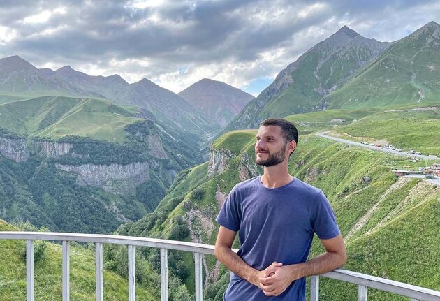 Uladzimir is standing in the mountains in Georgia, at the Gudauri viewpoint.