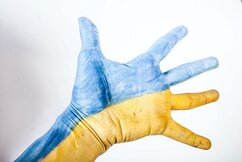 En utsträckt hand är målad i Ukrainas färger: halva blå, halva gul.