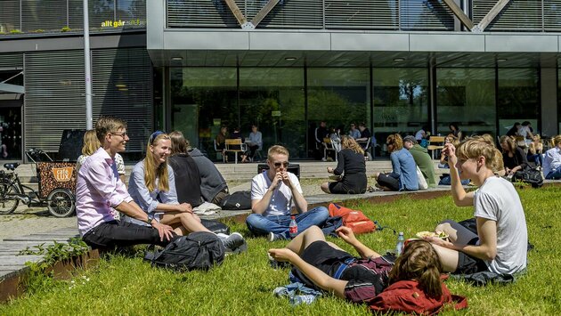 Studenter sitter vid södra entrén till LUX, campus för humaniora och teologi.