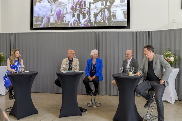 Fem personer deltar i ett panelsamtal inför publik.