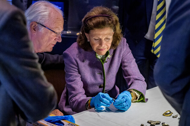 Drottning Silvia studerar ingående ett av järnåldersfynden.
