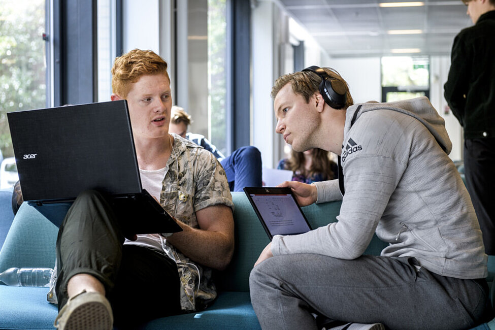 Två manliga studenter arbetar vid varsin bärbar dator i LUX.